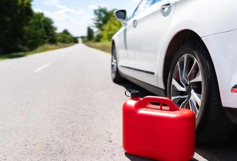 Red fuel can beside a car stranded on the road