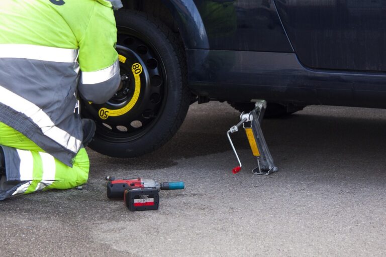 Roadside technician changing a flat tire with a jack