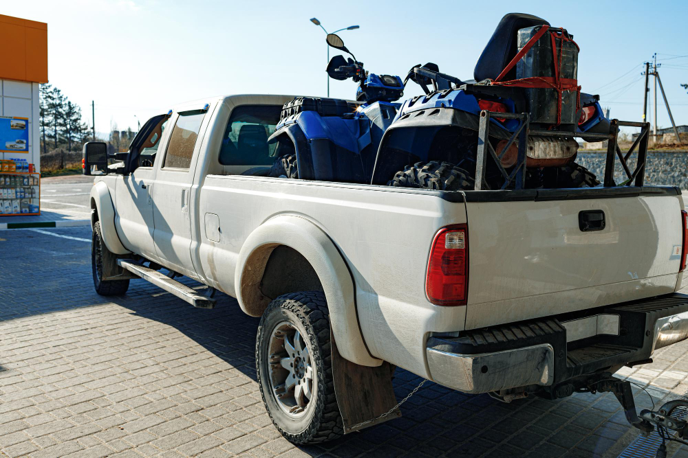 White pickup truck carrying an ATV for local hauling