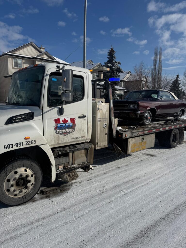 BP Towing flatbed carrying a car on a snowy Calgary street