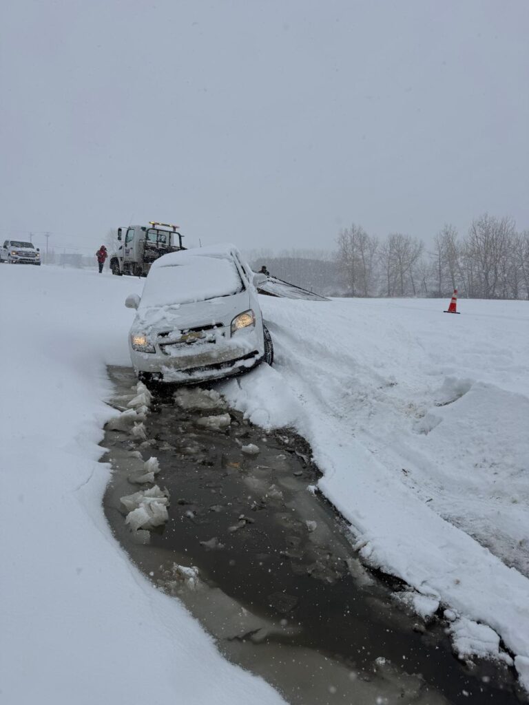 Car stuck in a snowy ditch awaiting recovery in Calgary