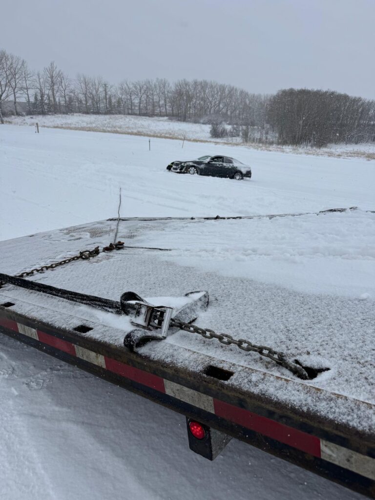 Flatbed winch line set to recover a car stuck in a snowy field