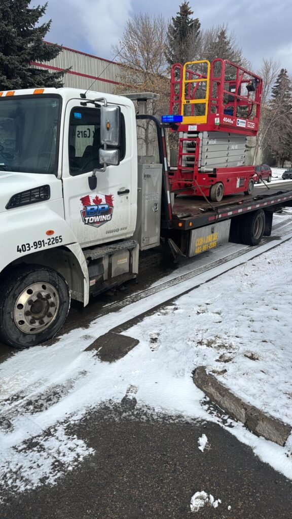 Scissor lift loaded on a BP Towing flatbed in the snow