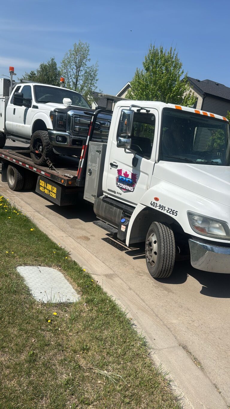 BP Towing flatbed carrying a white pickup truck in a Calgary neighbourhood