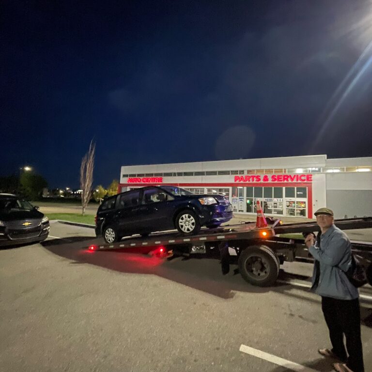 BP Towing flatbed loading an SUV at night outside a Calgary parts store