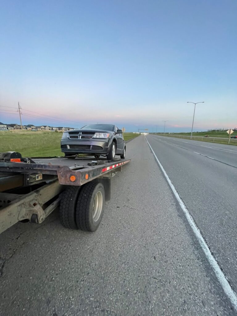 SUV loaded on a flatbed tow truck on the shoulder of an Alberta highway